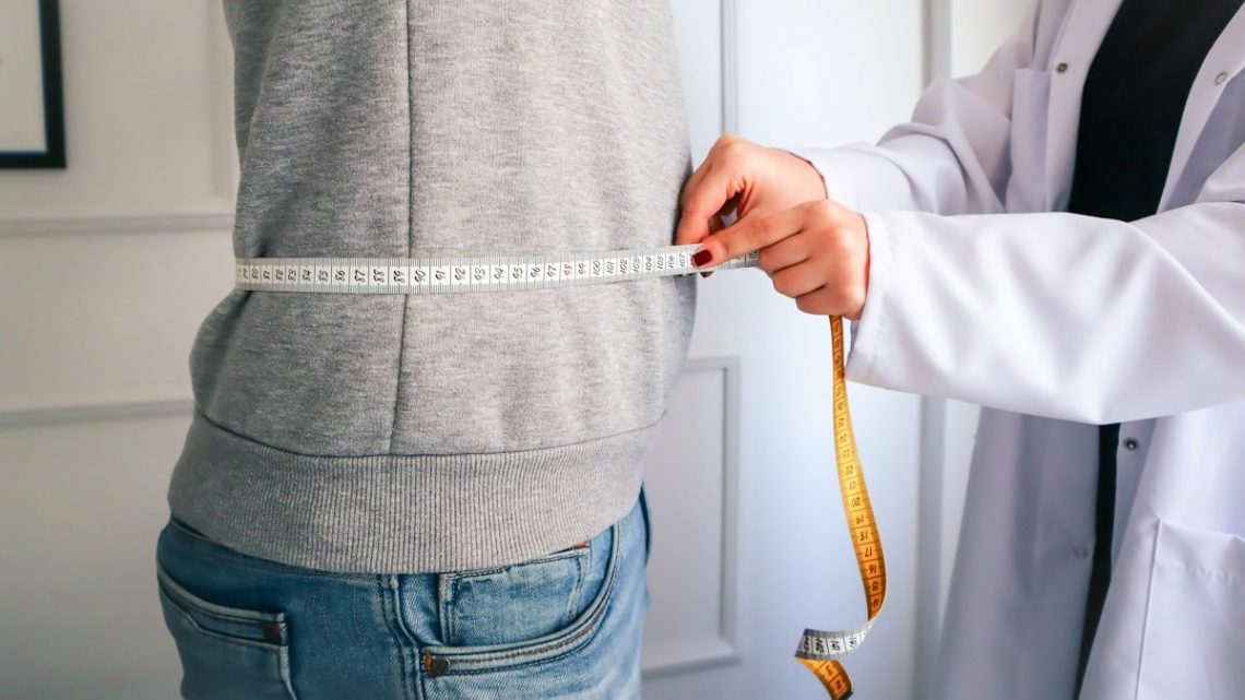 a woman measuring her waist with a measuring tape