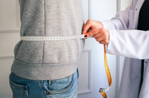 a woman measuring her waist with a measuring tape